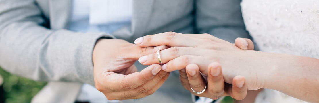 Groom putting ring on bride's finger during marriage ceremony.