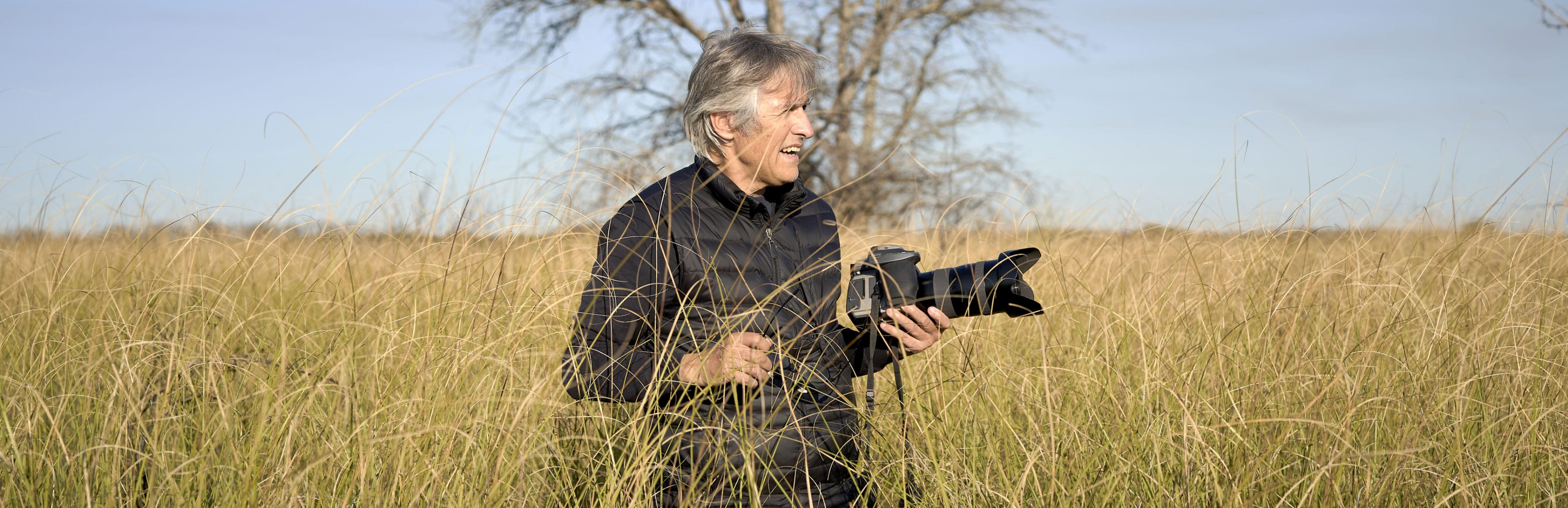 A retiree stands in a grassy field with a camera, illustrating how retirement side hustles can foster creativity, purpose and meaningful connection while providing extra income.